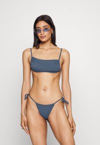 Biquíni azul em duas peças com um top bandeau com alças ajustáveis e um fundo com cordão lateral feito de tecido suave.