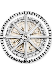 Design di una bussola in argento con una forma di stella intricata, un centro testurizzato in oro e un bordo circolare con punti e scanalature in rilievo.