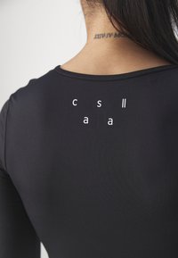 Zwarte longsleeve top met een ronde hals. Bevat witte tekst "c s l l a a" op de achterkant gedrukt. Gladde, rekbare stof.