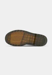 Semelle de chaussure avec des rainures profondes, en caoutchouc brun translucide et noir, affichant le nom de la marque et un symbole de certification de sécurité.