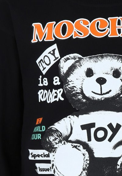 T-shirt nera con una grafica di un orsetto sorridente, con "MOSCHINO" in arancione e testo bianco che recita "TOY is a ROCKER" con accenti colorati.