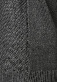 Mörkgrå tröja med ett strukturerat vävmönster på ena sidan och slät tyg på den andra, med ribbade manschetter i nederkant.