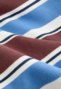 Tissu doux à rayures horizontales en bleu, marron, blanc, avec de fines lignes noires créant une texture lisse et légèrement froissée.