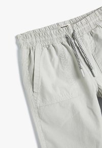 Pantaloni corti grigio chiaro con vita elastica, chiusura con cordino e tasche laterali. Tessuto liscio con sottili dettagli di cucitura.