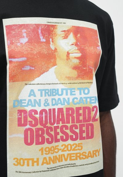 Tricou negru cu un imprimeu grafic colorat și text: "UN TRIBUT PENTRU DEAN ȘI DAN CATEN DSQUARED2 OBSESSED 1995-2025 30 DE ANI DE LA ÎNFIINȚARE."
