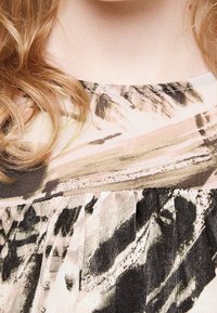 Abito realizzato in un tessuto morbido e leggero con un motivo astratto multicolore nelle tonalità di rosa, nero e beige. Dettagli plissettati sul collo.