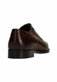 Bruine leren nette schoen met zwarte zool, gezien vanuit laag achteraanzicht op witte achtergrond.