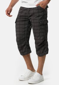 Pantalons capri cargo à carreaux noirs avec poches latérales, présentant une coupe décontractée, des ourlets retroussés et une texture de tissu léger.