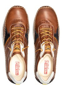 Zapatos de cuero marrón con acentos de malla, costuras claras y suelas de goma beige. Presentan herrajes de cuerda blancos y amarillos para un ajuste seguro.