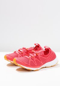 Klart rosa sportskor med nät- och gummimaterial. Med en texturerad ovandel, elastiska remmar och en gul sula för grepp.