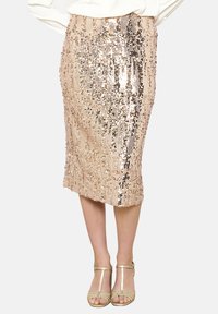 Dulkiai rožinė pieštuko sijonas, padengtas blizgučiais, su prigludusia forma, besitęsiantis žemiau kelių ir tekstūruota paviršiumi, atspindinčiu šviesą.