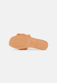 Oranžová slip-on obuv s texturovanou podrážkou, vyznačující se shromážděným textilním detailem na špičce. Plochá podrážka s gripovými vzory pro lepší trakci.