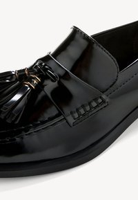 Svart lakk lær loafers med dekorativ sløyfe, frynse detaljer og søm aksenter. Glatt tekstur og rund tå design.