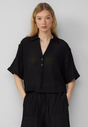 Camicia nera a maniche corte, con bottoni, dal taglio leggermente oversize, realizzata in tessuto texturizzato con un delicato motivo a coste e colletto.