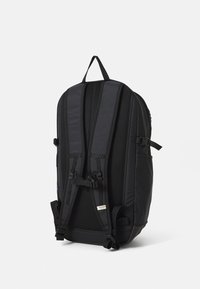 Czarny plecak z wyściełanym, siateczkowym panelem tylnym i regulowanymi paskami. Posiada klipsy zapewniające bezpieczne zamknięcie oraz minimalistyczny design.