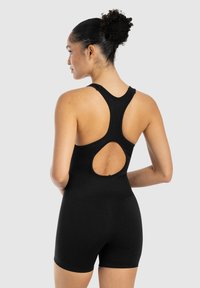 Bodysuit negro con un diseño de espalda nadadora y un corte ovalado en la parte posterior. Fabricado en tela ajustada y elástica que resalta la silueta.