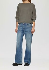 Grey ribbed long-sleeve top paired with light blue flared jeans and black ankle boots, showcasing a relaxed fit and subtle texture.