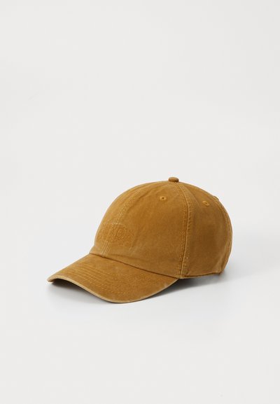Cappellino da baseball in cotone marrone con una texture morbida, visiera curvata e logo ricamato sul pannello frontale. Struttura a sei pannelli con fori di ventilazione.