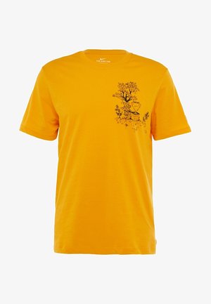 T-shirt orange à manches courtes Nike avec un motif noir représentant un arbre et un trophée sur la poitrine gauche.