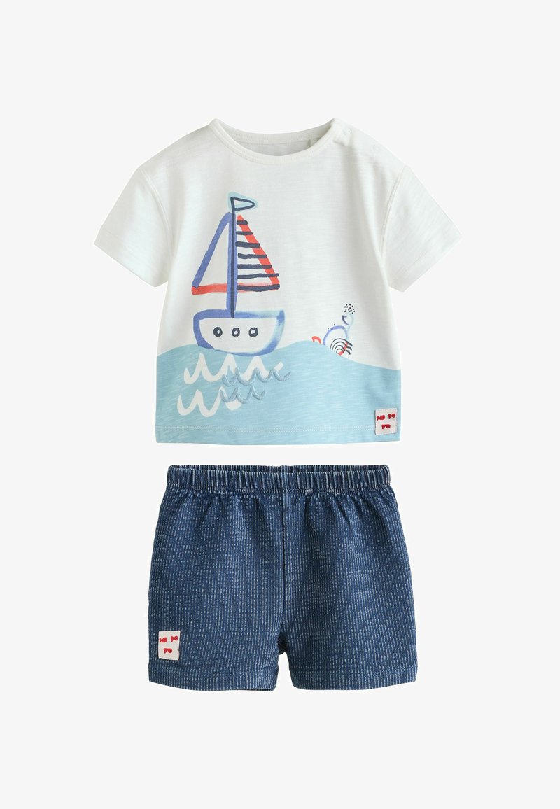 Ensemble en coton composé d'un haut blanc à manches courtes avec un imprimé de bateaux bleus et rouges, et d'un short à rayures bleu marine avec une ceinture élastique.