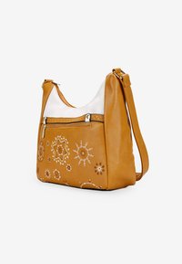 Bolso de hombro de cuero marrón claro que presenta un acento blanco, bordados decorativos de soles y flores, un bolsillo frontal con cremallera y una correa ajustable.