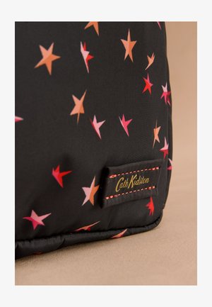 Sort stof med spredte orange, pink og røde stjerner samt et syet mærke med teksten "Cath Kidston" i gyldne bogstaver.