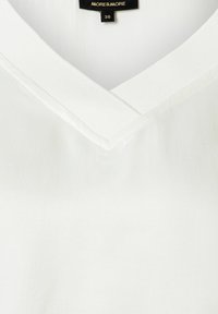 Weiße V-Ausschnitt-Bluse mit glatter Textur, ausgestattet mit einem gerippten Kragen und subtilen Nähdetail. Markenetikett innen sichtbar.