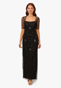 Schwarzes Abendkleid mit kurzen transparenten Ärmeln, verziert mit gestickten Blumenmustern und Perlendetails, bodenlang mit einer figurbetonten Silhouette.