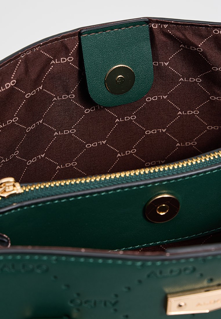 Intérieur d'un sac à main en cuir vert avec une fermeture éclair dorée et un bouton-pression. Doublé en tissu marron avec un motif subtil "ALDO".
