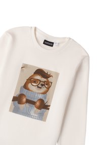 Felpa bianca con grafica di un bradipo con occhiali, che indossa un maglione blu. Tessuto morbido con scollo rotondo e dettaglio di stampa quadrata.