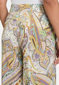 Vzorované široké kalhoty s krémovým základem a složitými paisley vzory v pastelových barvách s výraznými akcenty. Hladká tkanina, elastický pas.