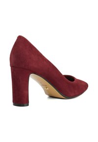 Burgundy suede high-heeled shoe with a rounded toe and prominent block heel, featuring a smooth texture and minimalistic design.