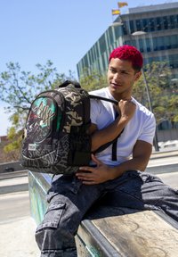 Mochila negra y de camuflaje con estampado gráfico de un ciclista BMX. Cuenta con múltiples compartimentos, correas ajustables y una asa resistente.