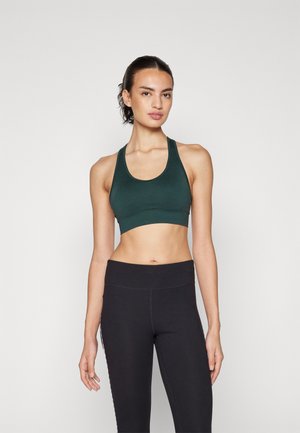 Mørkegrønn sports-bh med utringet hals og brede stropper, laget av elastisk materiale. Kombinert med svarte høytliv leggings.