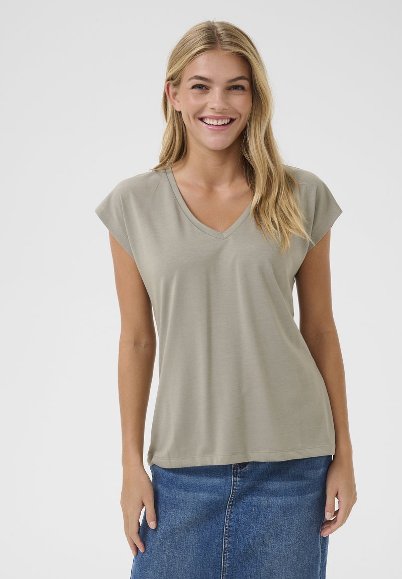 T-shirt V en kaki avec des manches courtes, fabriqué en tissu lisse. Design simple, coupe décontractée, associé à une jupe en denim.