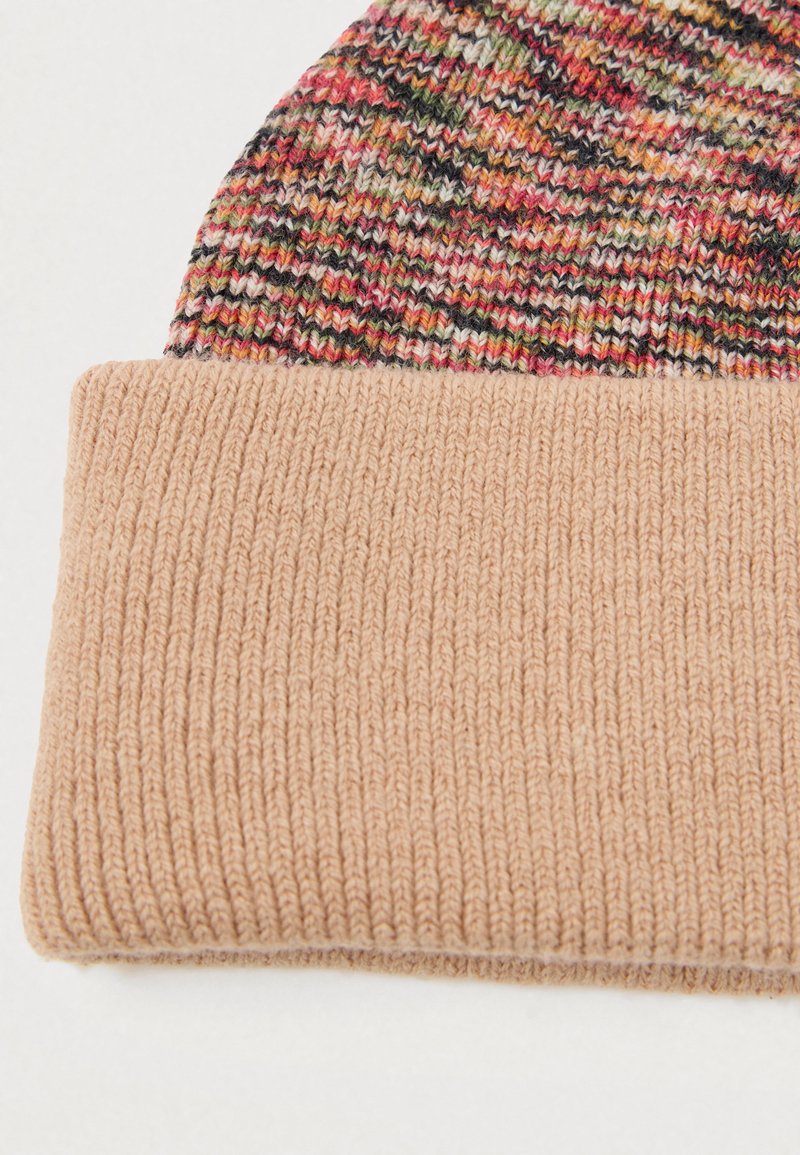Gehaakte beanie met een veelkleurige top met rode, groene en zwarte stippen; lichtbeige ribbelmanchet aan de onderkant. Over het geheel een gladde textuur.
