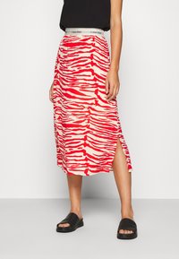 Röd och creamrandig midi-kjol med sidofickor och elastisk linning med Calvin Klein-logotyp. Bärs med svarta slide-sandaler.