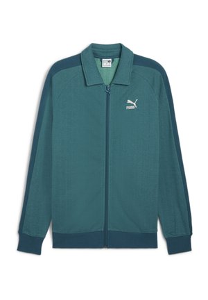 Türkiis sinine tõmblukuga jakk, millel on tekstuuriga kalasaba muster, soonikkoes mansetid ja krae; rinnal on valge Puma logo.