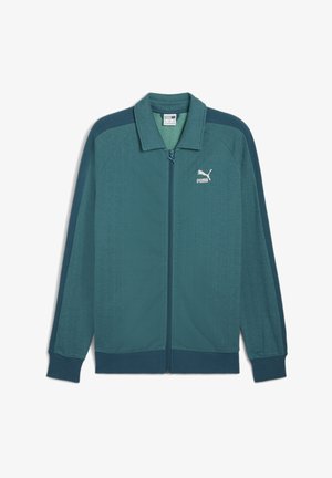 Türkiis sinine tõmblukuga jakk, millel on tekstuuriga kalasaba muster, soonikkoes mansetid ja krae; rinnal on valge Puma logo.
