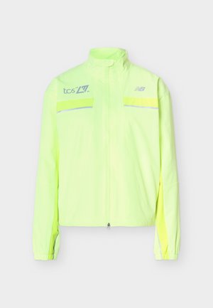 Neona dzeltens New Balance rāvējslēdzēja džemperis ar augstu apkakli, atstarojošām horizontālām joslām krūtīs un logotipiem kreisajā krūšu daļā un labajā plecā.