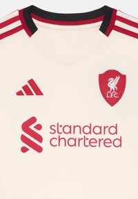Džersija boje krem s crnom i crvenom rebrastom ovratnikom, crvenim akcentima, grbom L.F.C. i logotipom "Standard Chartered" u crvenom tisku.