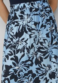 Blauwe bloemenrok met een geplooide tailleband, zwart-witte bloemenpatronen en een lichte, gestructureerde stof. Ideaal voor casual draag.