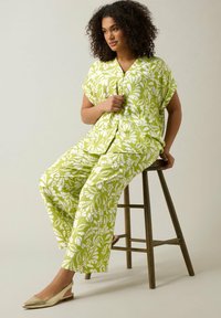 Groen en wit gestreept loungemodel, bestaande uit een kortmouwenshirt en wijde broek. Soepele textuur, relaxte pasvorm, gelaagd ontwerp.
