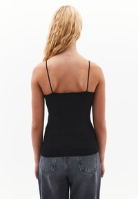 Czarny top bez rękawów z cienkimi ramiączkami, dopasowany krój i gładka tekstura. Połączony z jasnoszarymi dżinsami z wysokim stanem, z tylnymi kieszeniami.