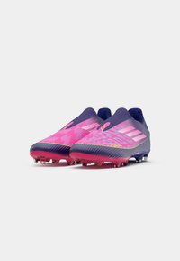 Botas de fútbol en púrpura y rosa, con un diseño elegante que presenta una parte superior texturizada, patrones hexagonales y tacos multidireccionales para tracción.