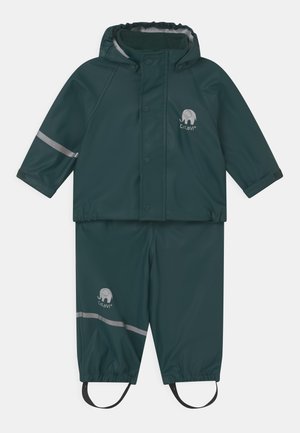 Mørkegrøn vandtæt regndragt med hætte, der har refleksstriber, elastiske manchetter og et logo af en elefant. Inkluderer justerbare fodstropper.