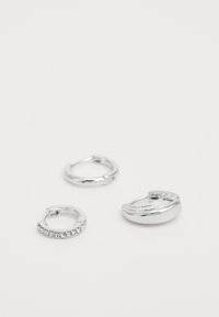 Trei cercei argintii: un model simplu, unul texturat cu o ușoară curbă și unul împodobit cu mici cristale transparente. Suprafațe rotunde, lustruite.