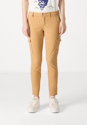 Slim fit cargobroek in kameelkleuren met zijflapzakken, gecombineerd met witte platformsneakers en een wit grafisch T-shirt.