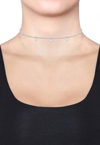 Collana choker in argento con un delicato design della catena, caratterizzata da piccoli ciondoli circolari distribuiti uniformemente lungo la lunghezza. Texture liscia e lucida.
