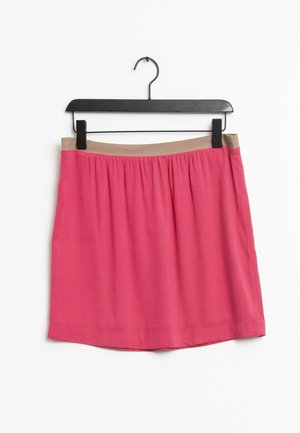 Roze rok met een elastische tailleband en een gladde, lichte stof. Hangt aan een zwarte hanger tegen een witte achtergrond.